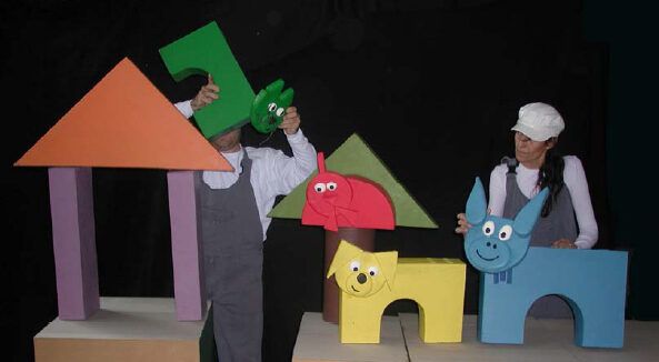 Actores de teatro manipulando títeres coloridos en un escenario.