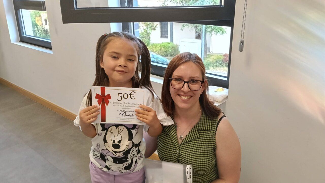 Niña y mujer sosteniendo un premio en un evento de lectura
