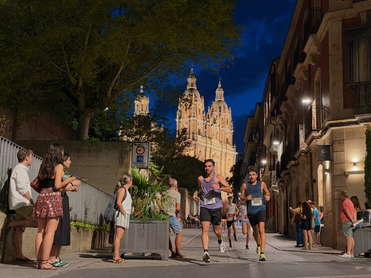 Corredores en las calles de Salamanca durante evento deportivo nocturno.