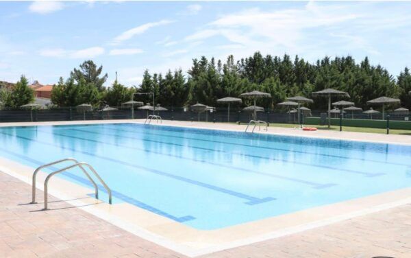 Piscina municipal lista para la apertura con agua clara y sombrillas