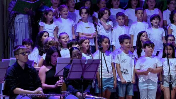 Niños y jóvenes cantando en un concierto de música escolar