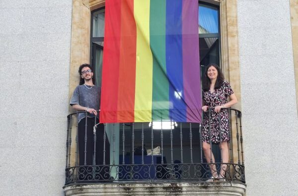Personas sosteniendo una bandera del orgullo en el Teatro Liceo de Salamanca