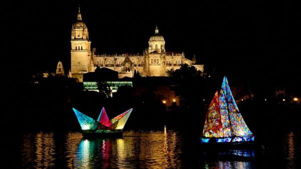 Barcos iluminados navegando en el río Tormes con la Catedral de Salamanca al fondo