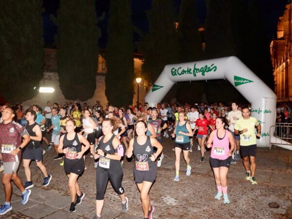 Participantes corriendo en la carrera popular en Salamanca bajo un arco de meta