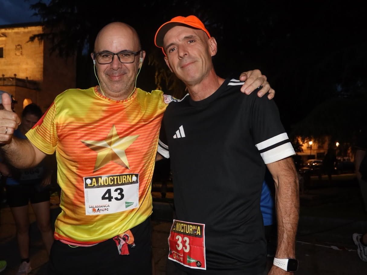 Dos corredores sonrientes en la carrera nocturna de Salamanca.
