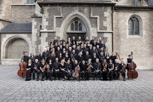 Orquesta Sinfónica Con Brio posando frente a un edificio histórico.