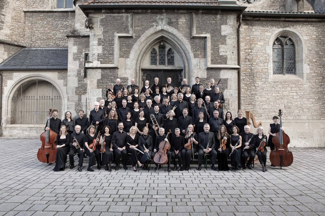 Orquesta Sinfónica Con Brio posando frente a un edificio histórico.