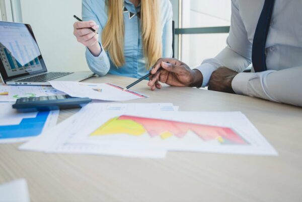 Dos personas revisando gráficos y documentos en una mesa de trabajo