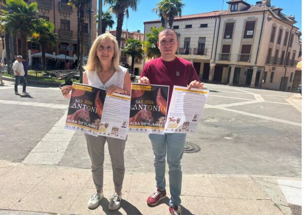 Dos personas sosteniendo carteles de la Feria Agroalimentaria en Alba de Tormes
