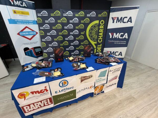 Mesa con productos y banners del II Torneo Solidario de Pádel de YMCA