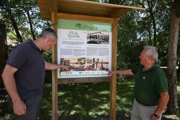 Dos hombres señalando un panel informativo sobre el río Águeda