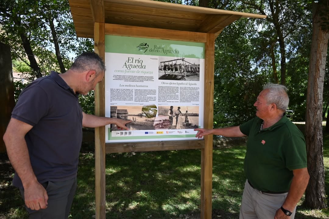 Dos hombres señalando un panel informativo sobre el río Águeda