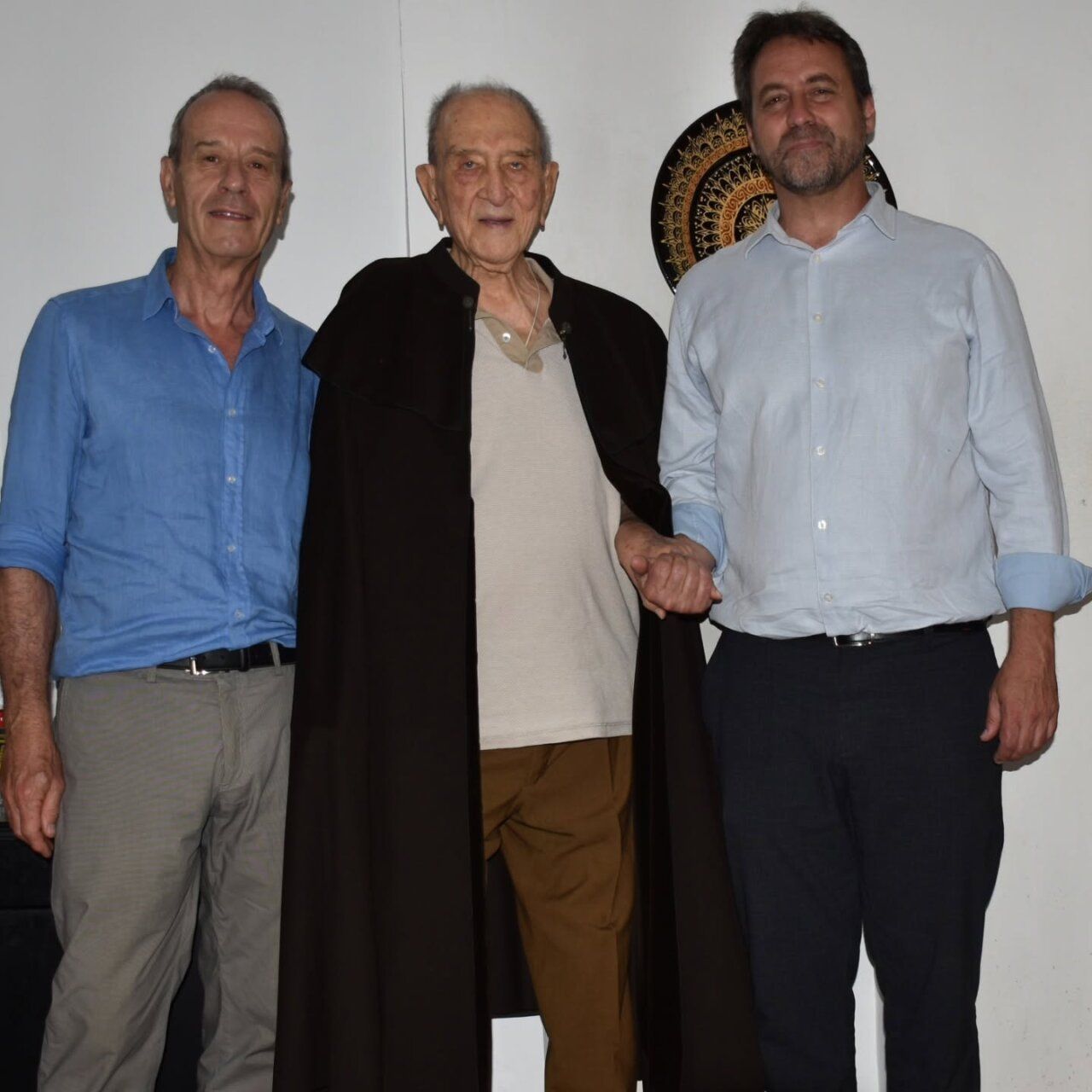 Tres personas posando con una capa histórica en el Museo Textil de Béjar