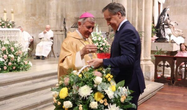 Dos hombres entregando una ofrenda floral en una ceremonia religiosa en Salamanca