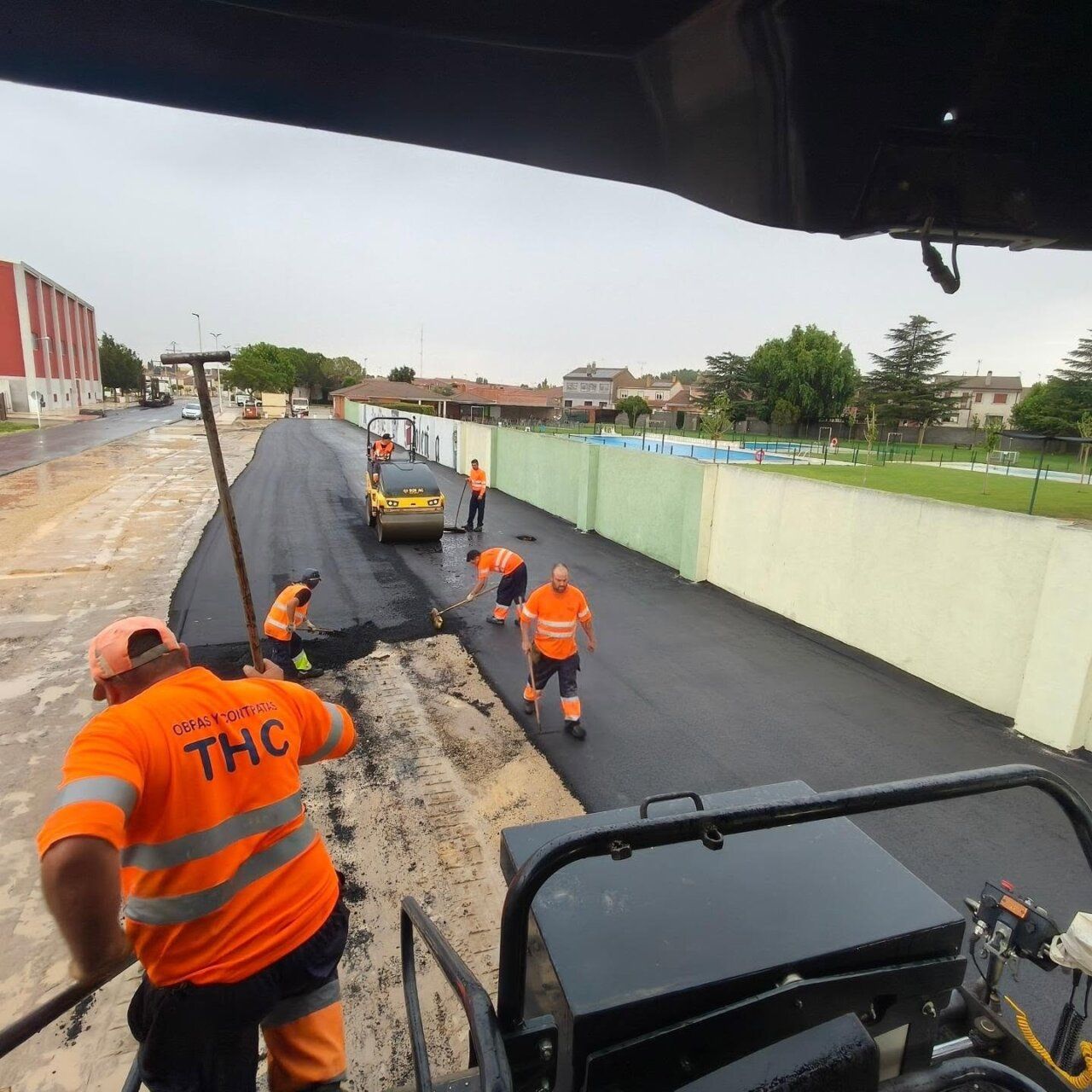 Trabajadores asfaltando el aparcamiento de las piscinas municipales de Villoria
