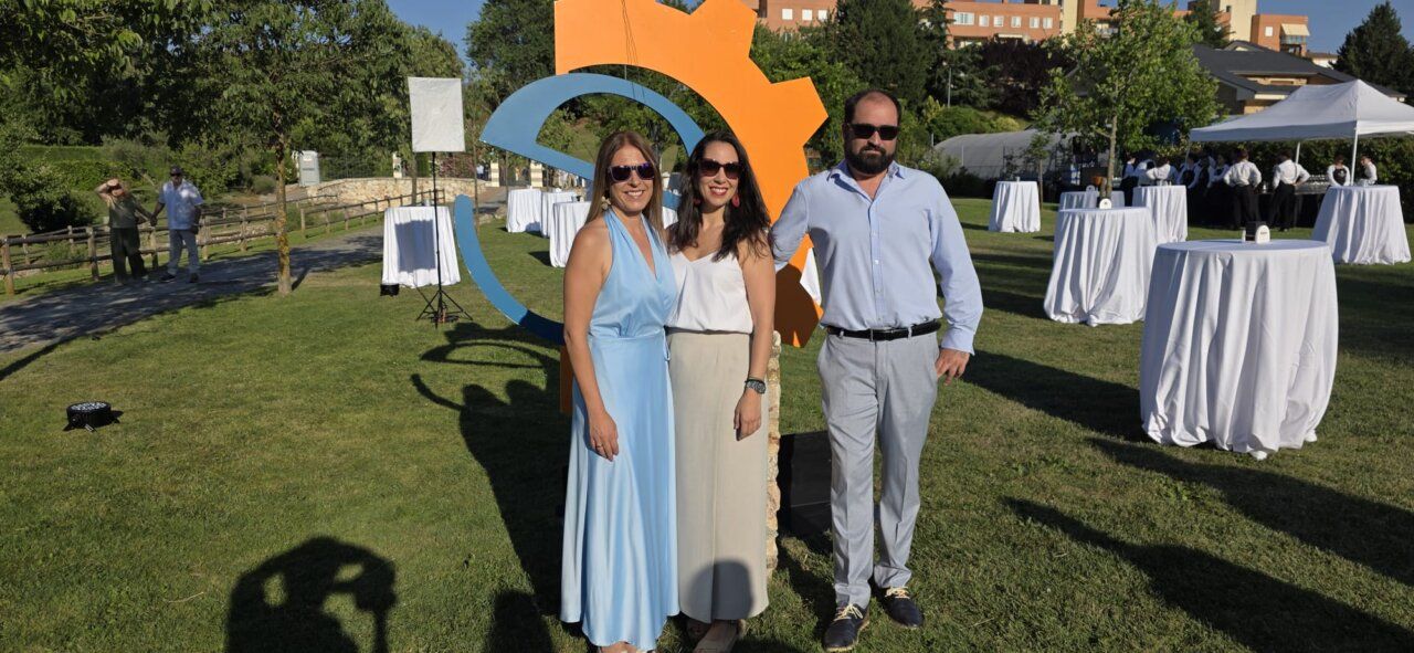 Tres personas posando en un evento al aire libre con decoración colorida.