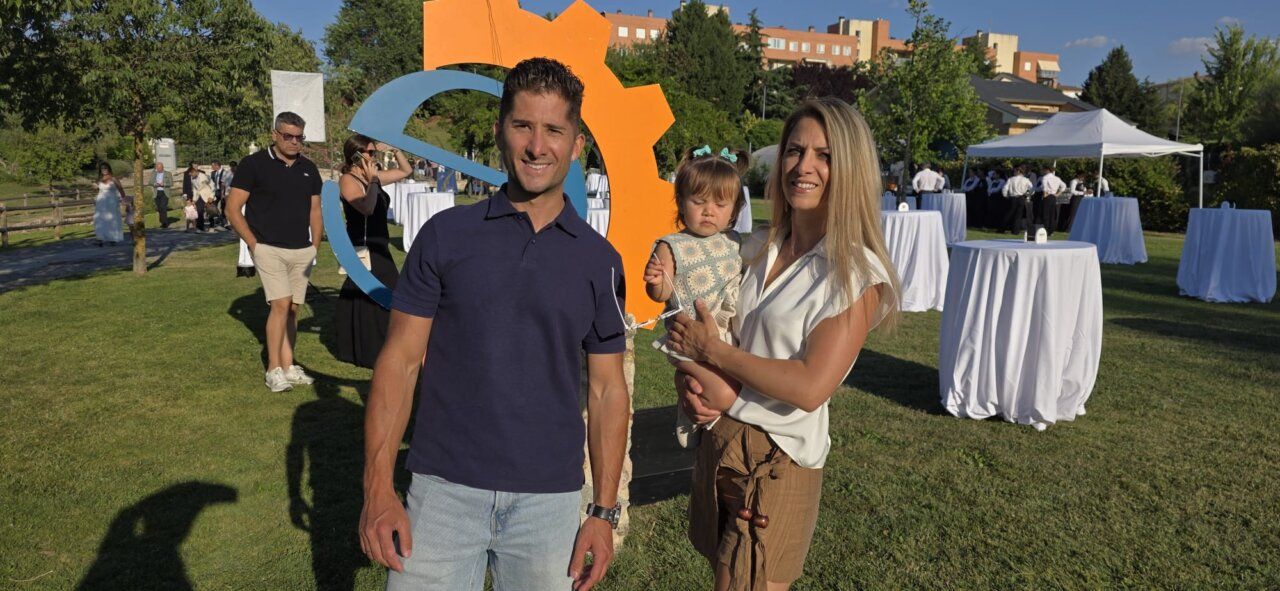 Pareja con una niña en un evento al aire libre con mesas blancas
