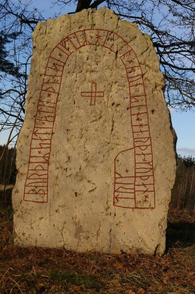 Piedra rúnica vikinga con inscripciones en rojo sobre fondo gris