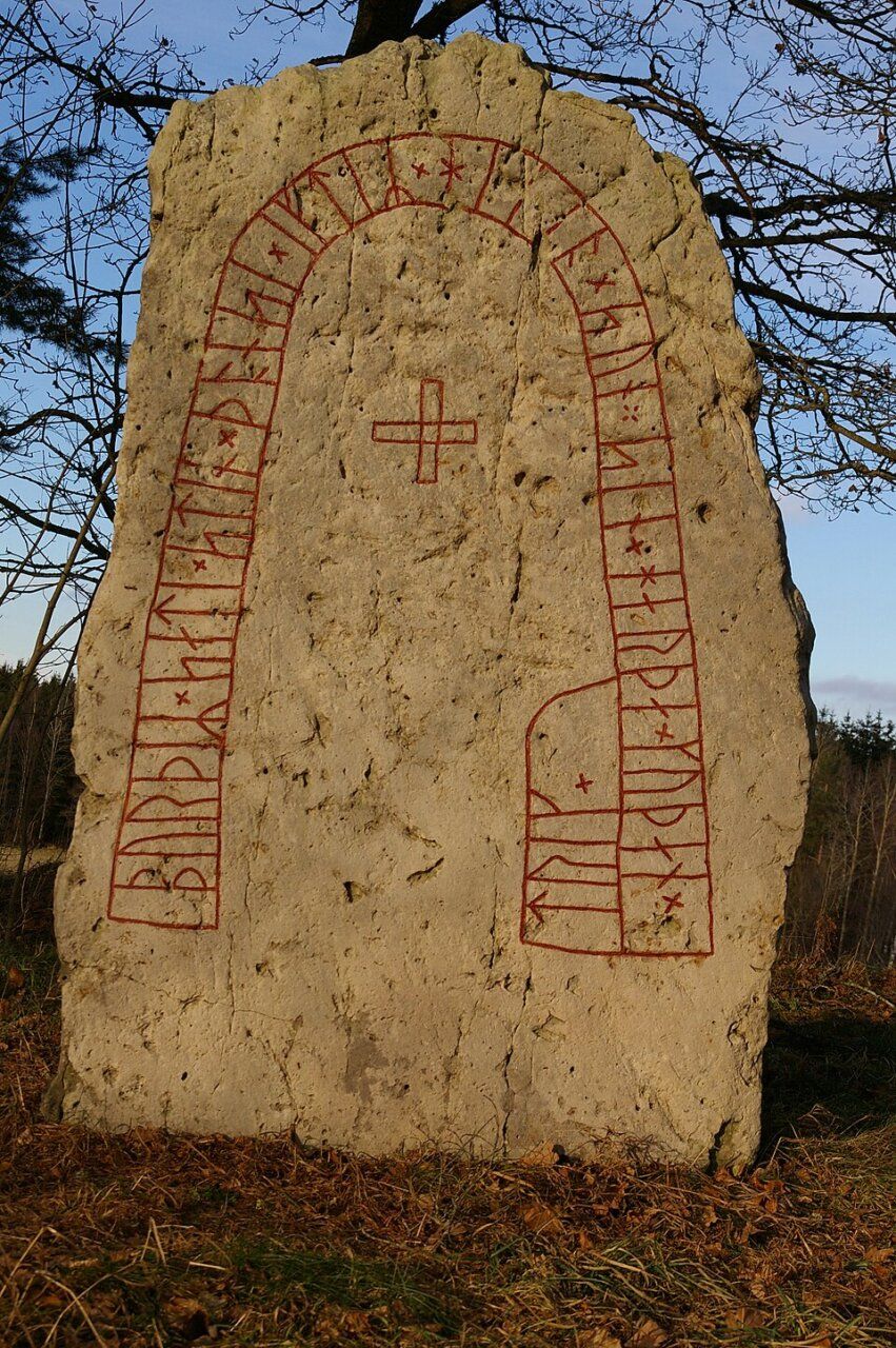 Piedra rúnica vikinga con inscripciones en rojo sobre fondo gris