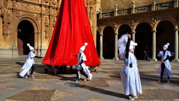 Actores en vestimenta blanca interactuando en las calles de Salamanca
