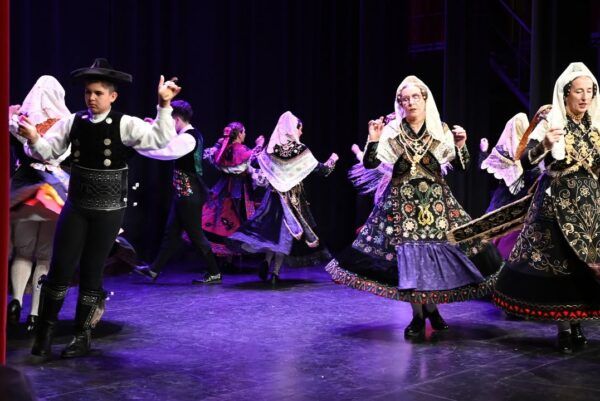 Grupo de bailarines en trajes tradicionales durante una actuación en el teatro.