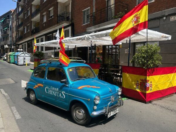 Café Bar Chinitas decorado con banderas de España y un coche azul