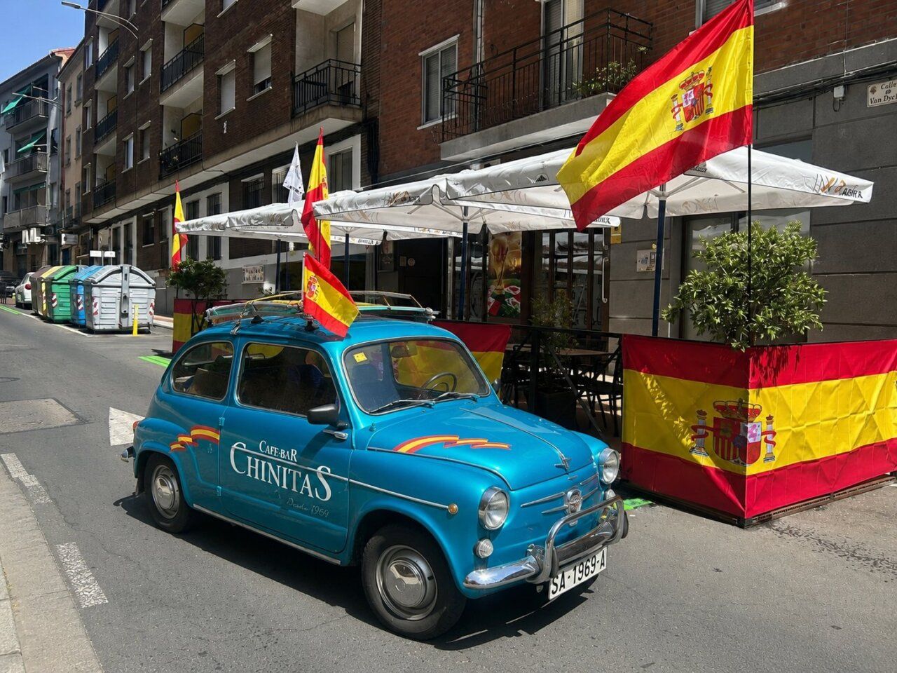 Café Bar Chinitas decorado con banderas de España y un coche azul