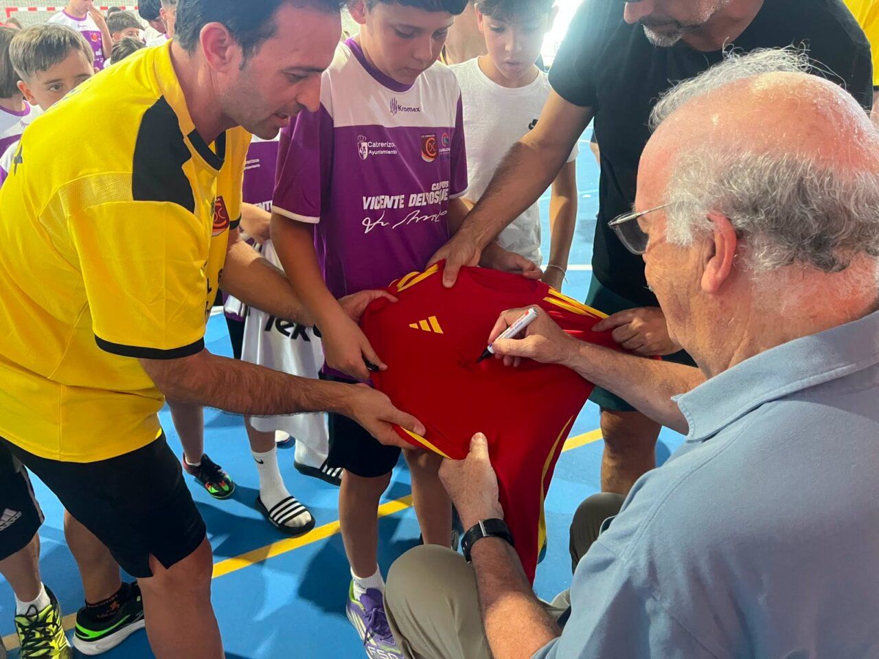 Vicente del Bosque firma una camiseta a jóvenes futbolistas en Carbajosa
