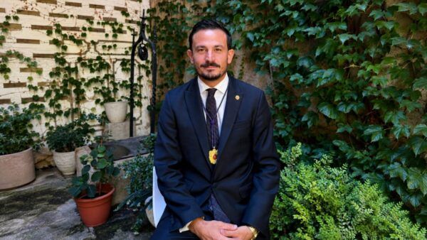 Antonio Rollán posando en un jardín con plantas verdes.