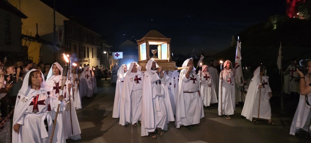 Participantes del desfile templario en Ponferrada con antorchas y vestimenta tradicional.