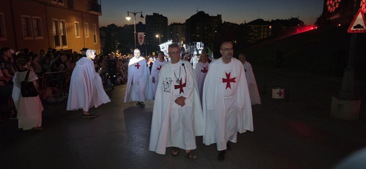 Participantes del desfile templario de Ponferrada con capas blancas y cruces rojas