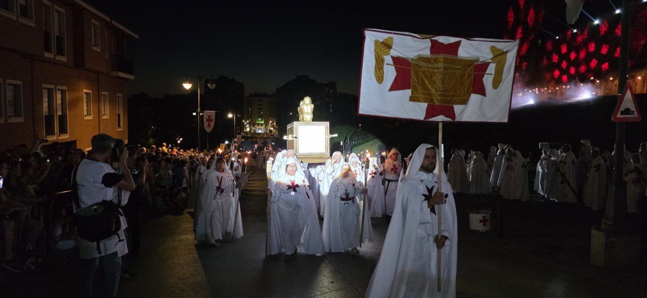 Participantes en el desfile templario de Ponferrada con vestimentas blancas y estandartes.