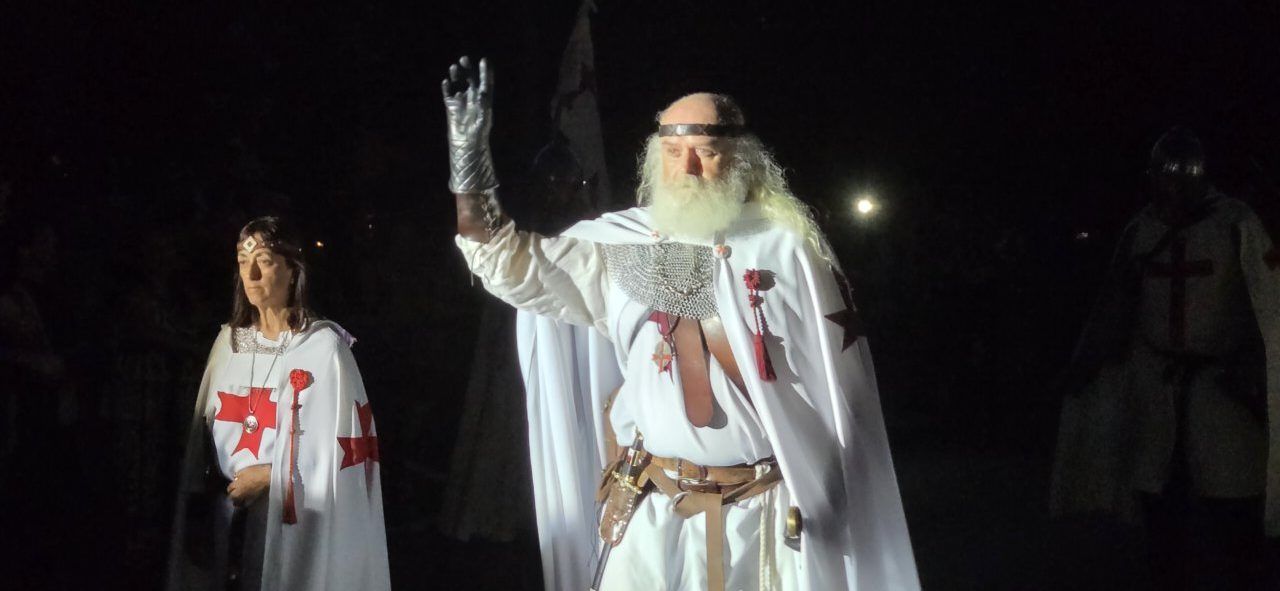 Hombre con barba y capa en un desfile templario nocturno