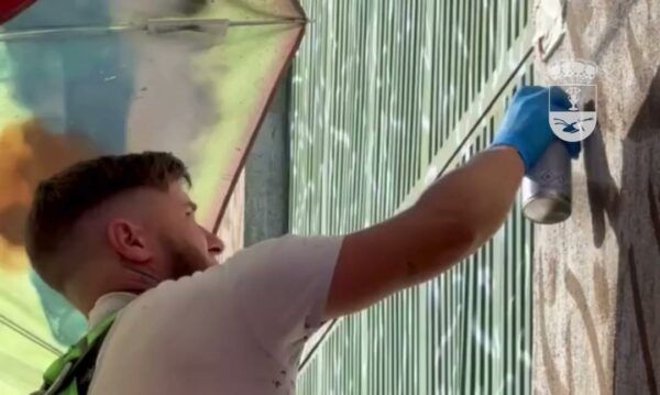 Muralista trabajando en una pared en La Vellés