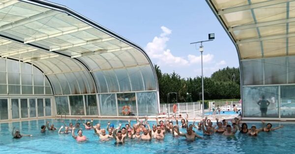 Grupo de personas en una piscina durante actividades deportivas de verano