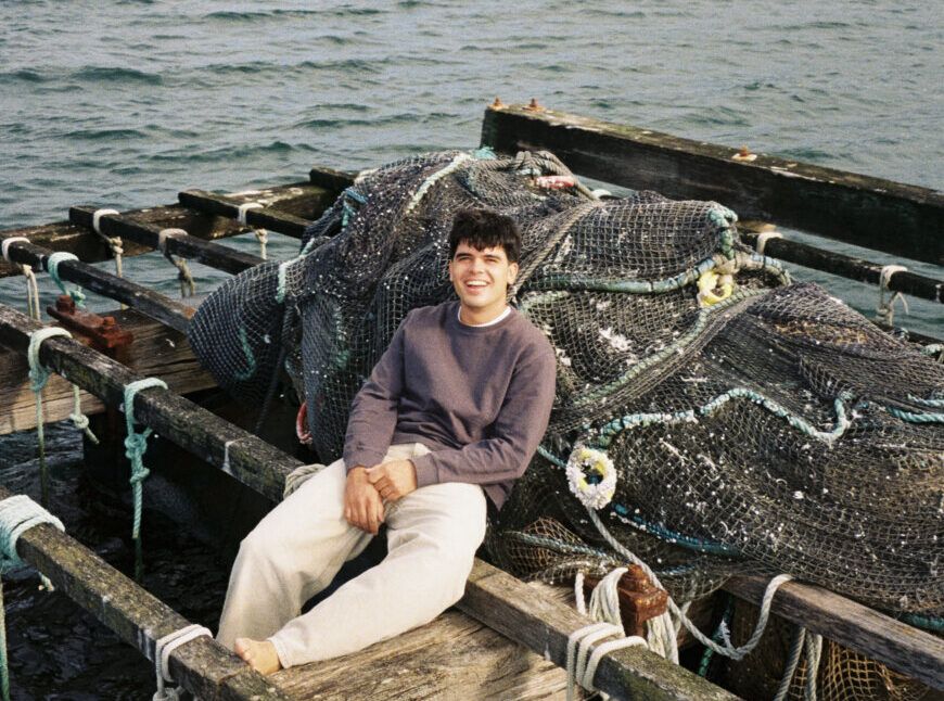 Íñigo Quintero sentado en un muelle junto al mar