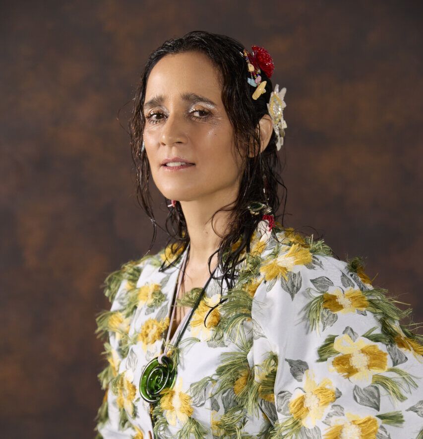 Julieta Venegas posando con un atuendo colorido y flores