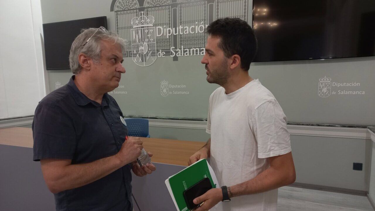 Dos hombres conversando en la Diputación de Salamanca sobre política.