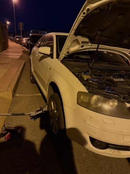 Coche con el capó abierto en la noche mientras se rescata un gato