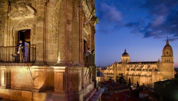 Vista nocturna de Salamanca con personas en un balcón
