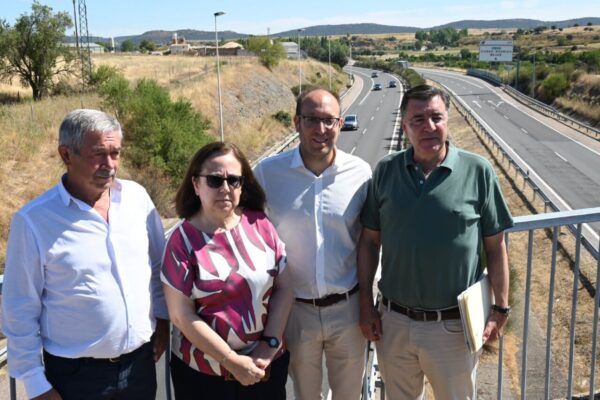 Cuatro personas posando junto a la carretera A-62 en un día soleado.