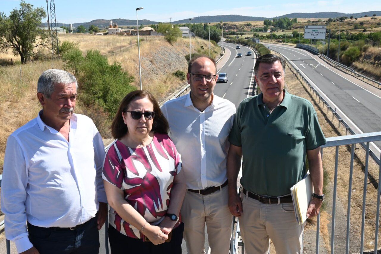 Cuatro personas posando junto a la carretera A-62 en un día soleado.