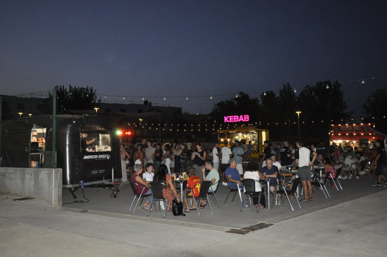 Multitud disfrutando de food trucks en Aldeatejada por la noche