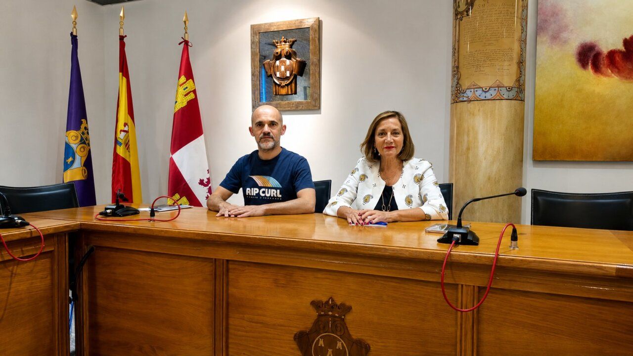 Dos personas sentadas en una mesa con banderas de fondo durante las Ferias y Fiestas de Peñaranda