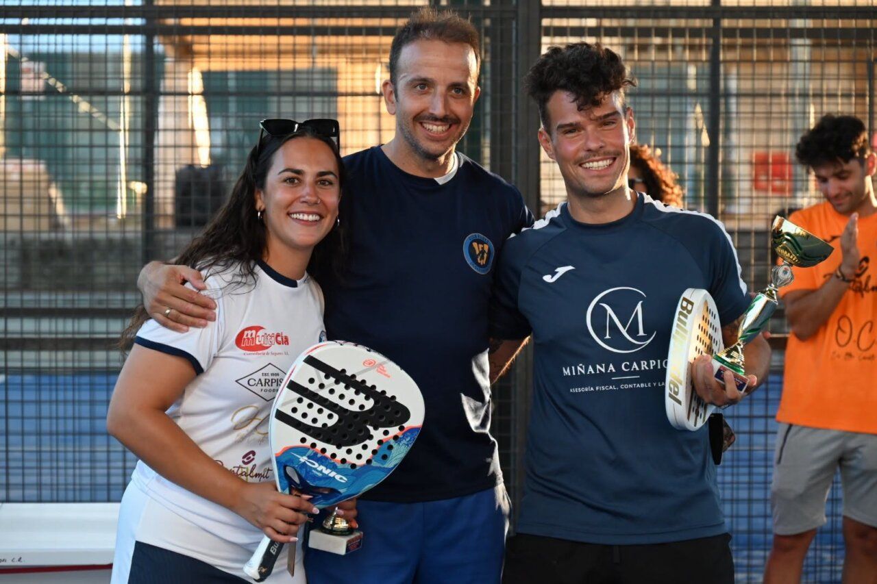 Tres personas sonrientes sosteniendo trofeos en un torneo de pádel