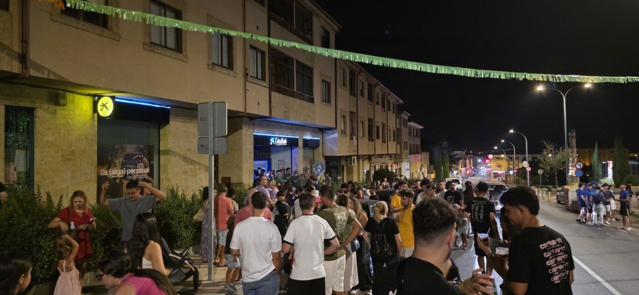 Gente celebrando la cuelga de banderines en Villamayor durante la noche.