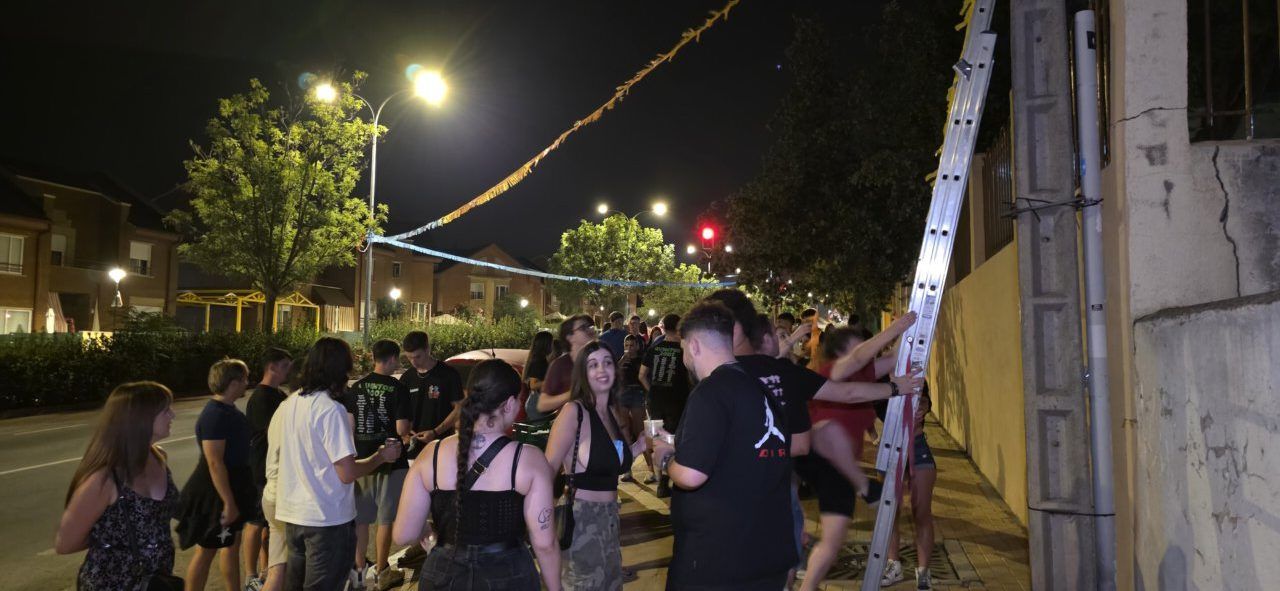 Grupo de personas colgando banderines en Villamayor durante la noche