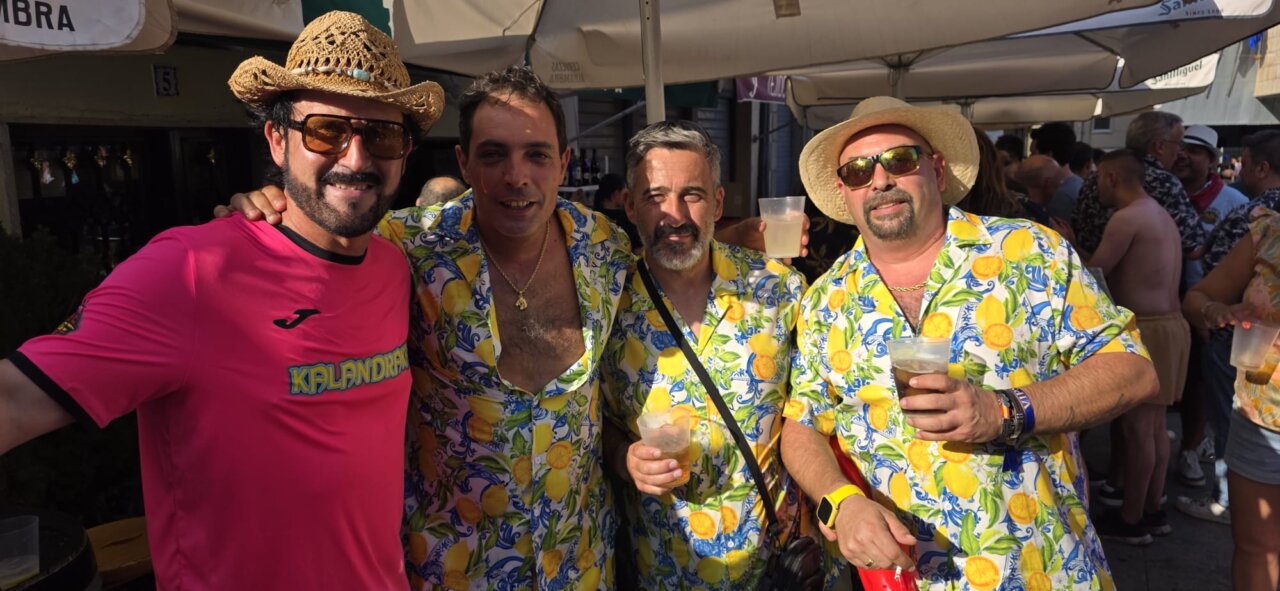 Cuatro hombres sonrientes en camisetas coloridas en un evento festivo