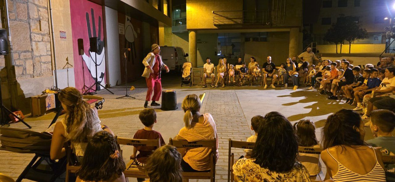 Espectáculo de circo en la Plaza de España de Villamayor con un payaso y público disfrutando.