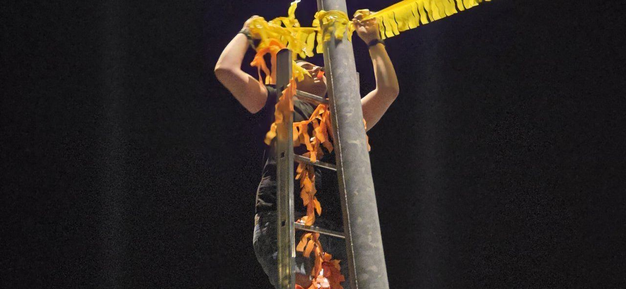 Persona colocando banderines en una escalera durante las fiestas de Villamayor